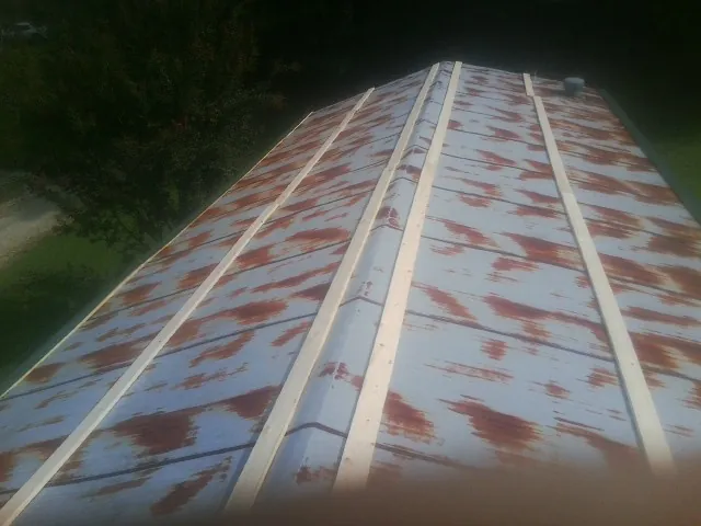 Rusted metal roof panels with new wood purlins before replacement — Storm Damage Roof Repair in West Brookfield by Roofing Brothers