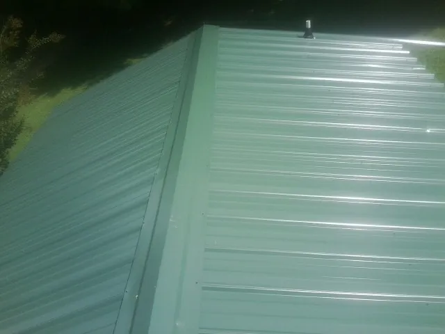 New green metal panels meeting at the ridge of a roof — Flat Roof Repair work by our crew in West Brookfield