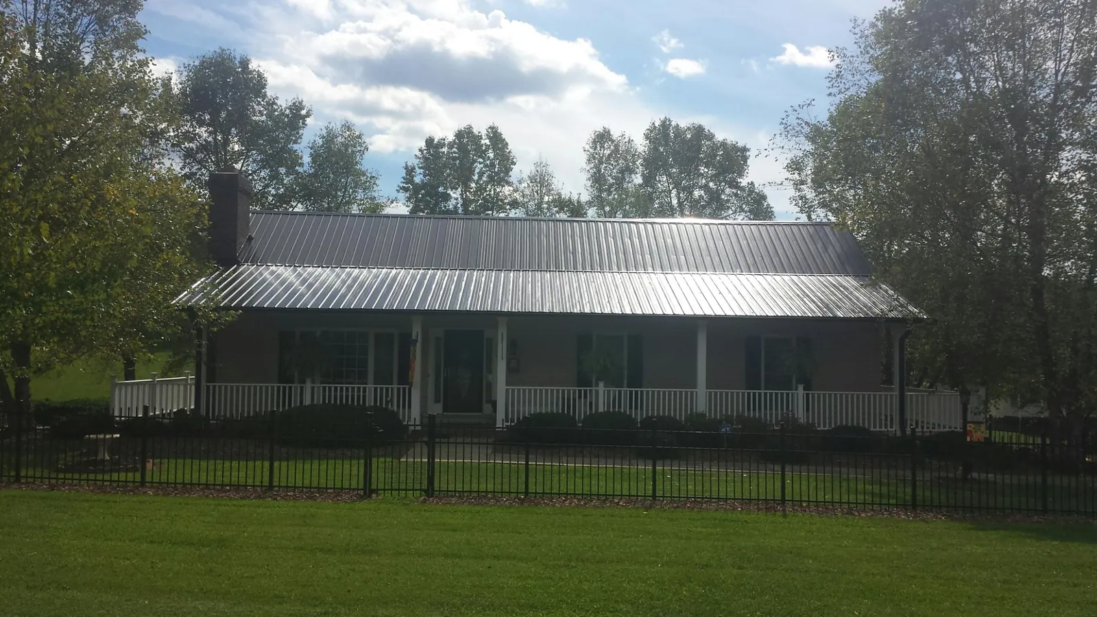 Gray metal roof on a brick ranch with a full width front porch — Gutter Guard Installation work by our crew in West Brookfield
