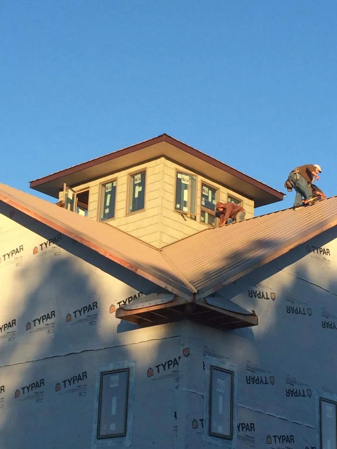 Roofers working around a rooftop cupola on a new metal roof at sunset — Roof Waterproofing in West Brookfield by Roofing Brothers